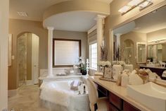 a large bathroom with marble counter tops and white fixtures, along with an oval shaped bathtub