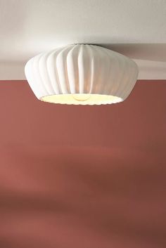 a white light hanging from the ceiling in a room with pink walls and flooring