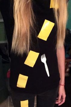 a woman with long blonde hair wearing a black shirt and yellow tape around her neck