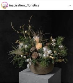 a basket filled with pine cones, candles and other christmas decorations on top of a table