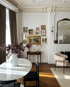 a dining room table with chairs and pictures on the wall