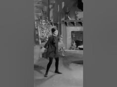 an old black and white photo of a woman walking down the street