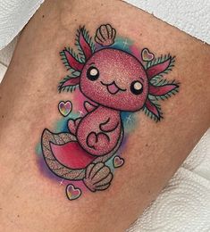 a small tattoo on the side of a woman's thigh with an image of a pink creature