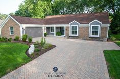 a brick driveway leading to a house with two car garages on each side and an entry way in the middle