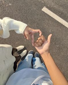 two people holding hands in the middle of an empty parking lot with one pointing at the other