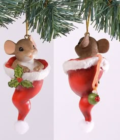 two ornaments in the shape of mice hanging from a christmas tree branch, one wearing a santa claus hat and holding a holly berry ornament