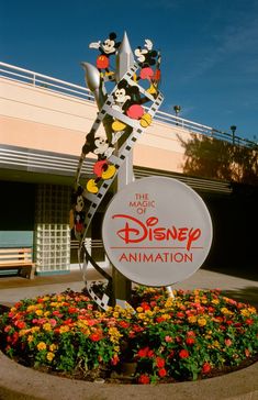 there is a sign that says the magic of disney animation in front of some flowers