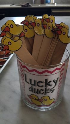 there is a glass cup with some sticks sticking out of it that have rubber ducks on them