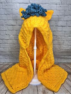 a crocheted yellow blanket with blue flowers on it, sitting next to a white lamp