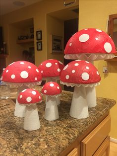 four red and white mushrooms sitting on top of a counter