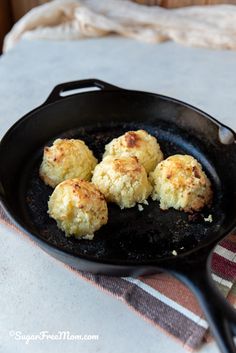 three biscuits cooking in a skillet on top of a table next to a towel