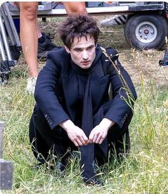 a man sitting in the grass with his hands on his knees