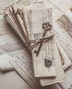 an old envelope with keys tied to it on top of some papers that are covered in writing