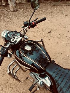 a black motorcycle parked on top of a dirt field