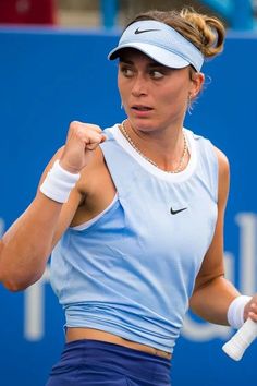 a woman holding a tennis racquet in her right hand and wearing a visor