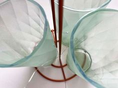 two glass vases sitting on top of a white table next to a brown wire