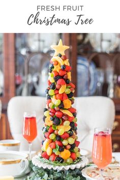 a christmas tree made out of fruit on top of a table with wine glasses and plates