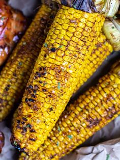 grilled corn on the cob with bbq sauce and barbecue meats in the background