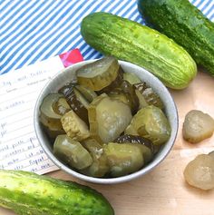 pickles and cucumbers sit on a cutting board next to a notepad