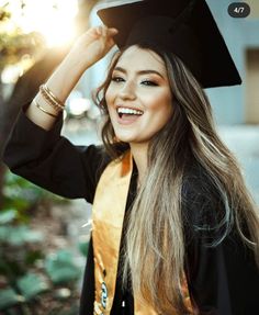 a woman wearing a graduation cap and gown posing for a photo with her hair in the air