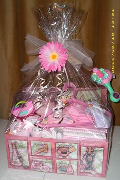 a pink gift box filled with lots of baby items and a flower in the center