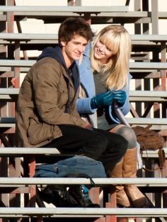 a young man and woman sitting on the bleachers