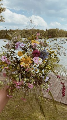 a person holding a bouquet of flowers by the water