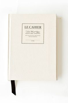 a white book with a black ribbon on the front and back cover that reads le cahier