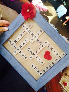 a scrabble frame with words written on it and a red flower in the middle