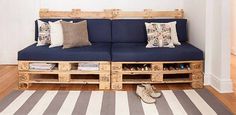 a couch made out of wooden pallets with shoes on the floor next to it