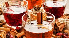 a glass filled with liquid surrounded by cinnamon sticks