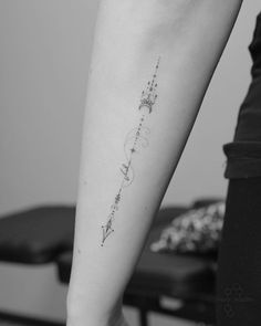 a woman's arm with an arrow and stars tattoo on the left side of her arm