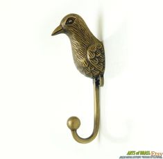 a brass bird hook on a white wall