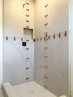 a bathroom with marble walls and tile flooring is shown in this image, there are red pins on the wall