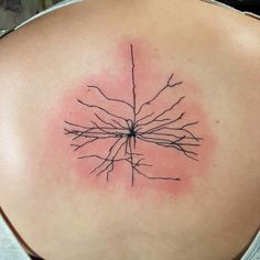 the back of a woman's shoulder with a tattoo on it that has many branches growing out of it