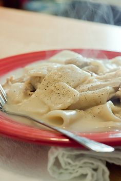 a red plate topped with pasta covered in sauce