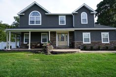 a gray house with white trim on the front and side windows is shown in this photo