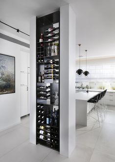 a wine rack in the middle of a kitchen with white walls and floor to ceiling windows