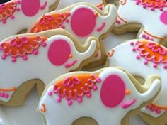 decorated cookies in the shape of elephants with pink and orange icing on white platter