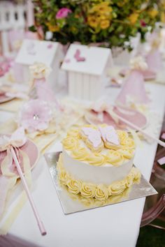 a table topped with a cake covered in pink and yellow frosting