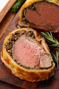 a meatloaf is cut in half on a cutting board with rosemary sprigs