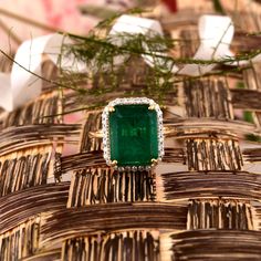 an emerald and diamond ring sitting on top of wicker