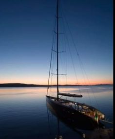 a sailboat sitting in the water at sunset