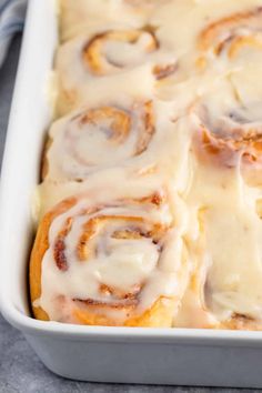 a pan filled with cinnamon rolls covered in icing