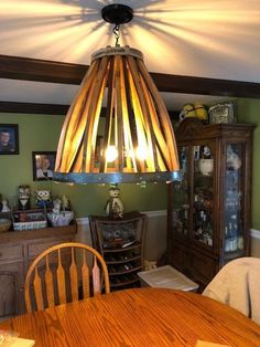 a wooden table and chair under a light fixture in a room with pictures on the wall