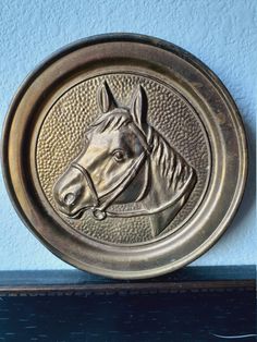 a metal horse head mounted to the side of a blue wall with a wooden shelf below it