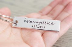 a hand holding a silver key chain that says bianjesiaca