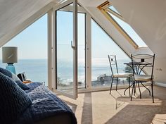 a bedroom with an ocean view is shown in this image, while the bed and desk are also visible