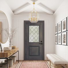 an entryway with a bench, mirror and pictures on the wall next to it