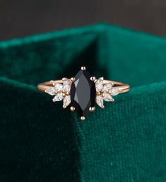 a black diamond ring sitting on top of a green velvet bag